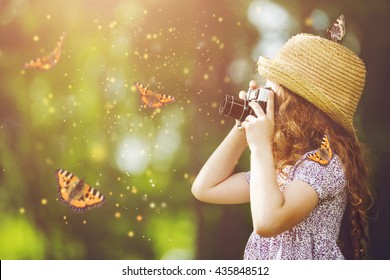 Little Girl In Straw Hat, Rustic Style Dress, Photographing Butterfly With Retro Photo Camera In Fairytale Forest.