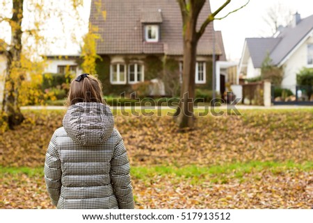 Little girl in a street looking at house on the other side of street