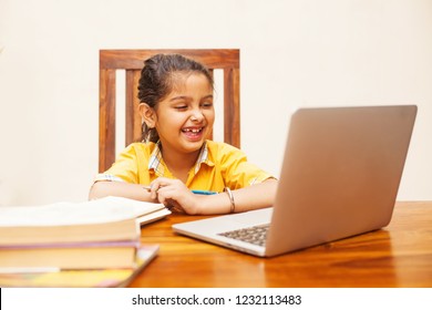 Little girl studying online using her laptop at home