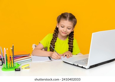 A little girl is studying with a tutor online at her desk. Distance home education for schoolchildren. The child does his homework on the computer.