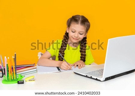 A little girl is studying with a tutor online at her desk. Distance home education for schoolchildren. The child does his homework on the computer.