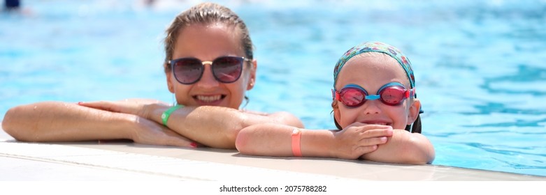 Little Girl In Swimming Goggles And Mother Lying On Side Of Pool