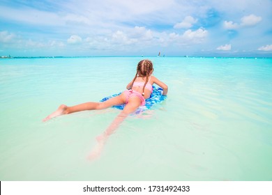 Little girl swimming on a surfboard in the turquoise sea - Powered by Shutterstock