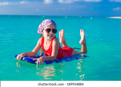 Little girl swimming on a surfboard in the turquoise sea