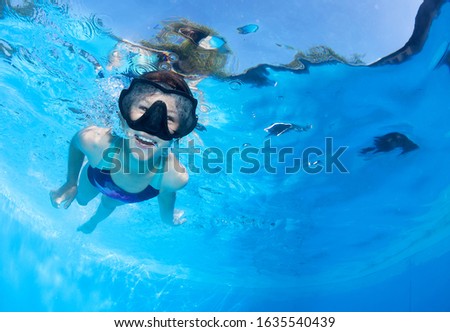 Little girl swims underwater in the pool . 