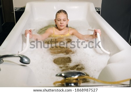 a little girl takes the procedure in a mineral bath. The patient receives water treatments with a mineral pearl bath