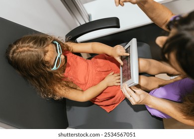 Little girl taking eye exam with optometrist using digital tablet - Powered by Shutterstock