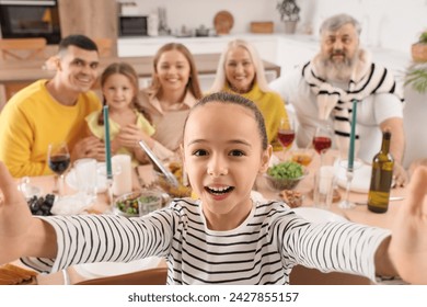 Little girl taking selfie with her family at dinner - Powered by Shutterstock