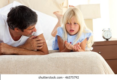 Little Girl Talking Seriously With Her Father Lying On Bed