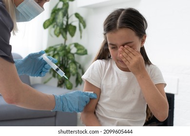 A little girl with tears in her eyes is very afraid of vaccination. The baby cries closing his eyes in pain. Portrait of a sobbing child who is injected in the shoulder. Children's medical concept,