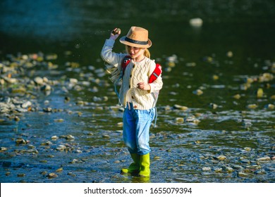 Little Girl Throw Stones At The Stony River. Beautiful Kids Girl Throws A Rock At The River. Skipping Rocks