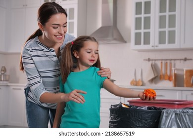 Little Girl Throwing Tangerine Peel Into Trash Bin In Kitchen. Separate Waste Collection