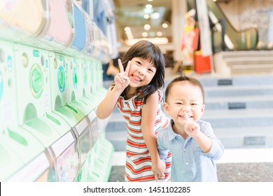 Little girl and toddler boy happy when they play with Gashapon capsule toy vending machines in Akihabara, Tokyo, Japan.
