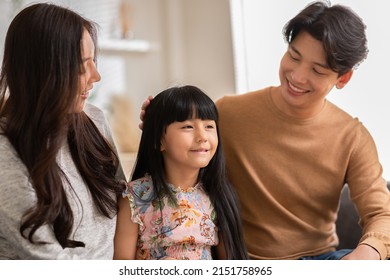 Little Girl Told Happiness Story To Her Mom And Dad With Positive And Proud Emotional.Asian Daughter Tell A Story To Mother And Father Father Touching Her Head With Love At Cozy Home.Good Moment