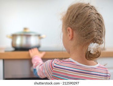 Little Girl Touches Hot Pan On The Stove. Dangerous Situation At Home. 