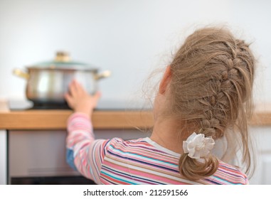 Little Girl Touches Hot Pan On The Stove. Dangerous Situation At Home. 