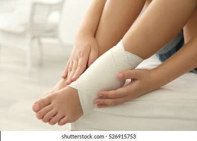 Little girl touching ankle with elastic bandage, close up view