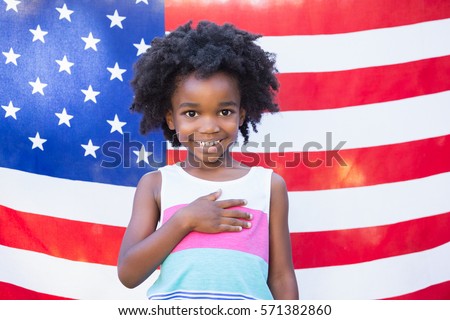 A little girl is touching her heart front of american flag