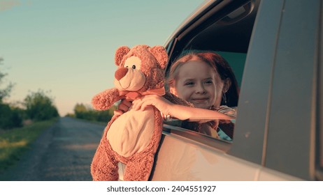 little girl with toy bear. happy face child daughter from window with teddy bear. happy family. mother daughter traveling car. happy mother child back seat car going trip. face childish smile. - Powered by Shutterstock