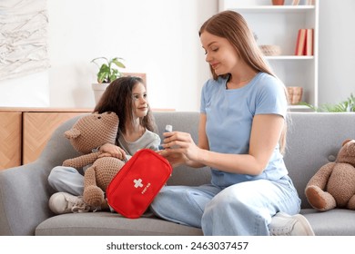 Little girl with toy and her mother taking inhaler from first aid kit at home