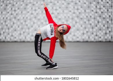 Little Girl In A Tracksuit Is Dancing Modern Dance On The Street. Young Urban Hip Hop Dancer