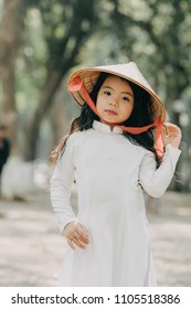 little girl in traditional costume Vietnam stood on the road with beautiful trees at sunset in Hanoi, Vietnam