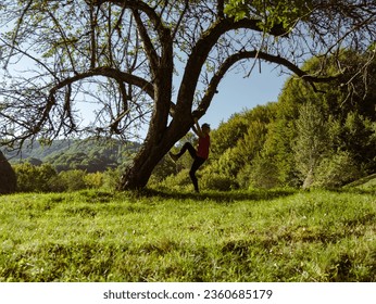 Little girl traveler climbing on tree forest Carpathian mountains peak Zakarpattya village, Ukraine, Europe. Child walks on green lawn scenic landscape sunny day. Eco Local countryside tourism. Hiking - Powered by Shutterstock