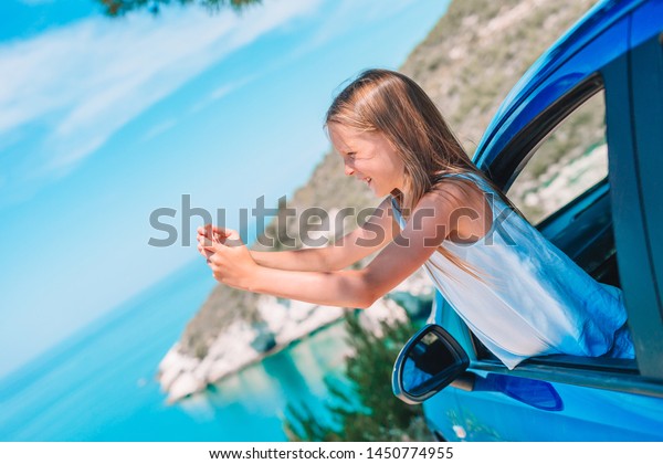 Little girl\
traveling by car and making photo of beautiful landscape. Summer\
holiday and car travel\
concept