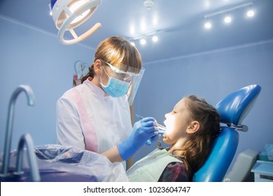 little girl is treating teeth with a pediatric dentist
