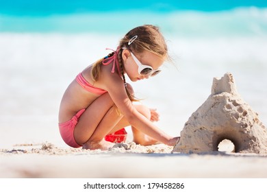 Little girl at tropical beach making sand castle - Powered by Shutterstock