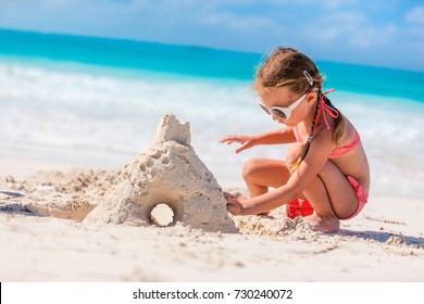 Little girl at tropical beach making sand castle - Powered by Shutterstock