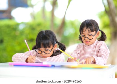 Little Girl Two Asian Wearing Glasses And Doing Homework Together At Home  Which Increases The Development And Enhances Outside The Classroom Learning Skills Concept.