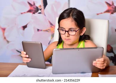 Little girl using at home a Tablet PC and an Ebook for homework
