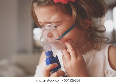 Little Girl Using Inhaler At Home.