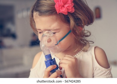 Little Girl Using Inhaler At Home.