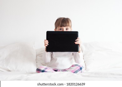 Little Girl Using A Ipad/tablet On The Bed