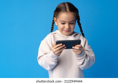 Little Girl Using Mobile Phone.against Blue Background