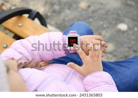 Little girl using SOS function on smartwatch outdoors, closeup