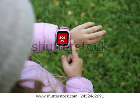 Little girl using SOS function on smartwatch outdoors, closeup