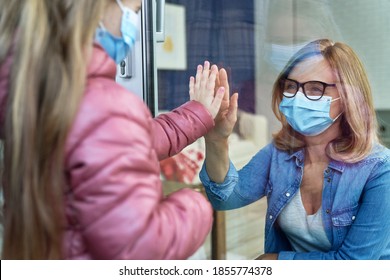 Little girl visiting grandparents through window                                - Powered by Shutterstock