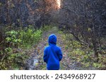 The little girl is walking. The child is alone in the forest. The girl was lost alone in the forest. A child without supervision. Loneliness and a walk in a dark forest. 