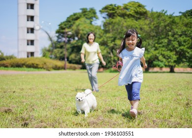 A Little Girl Walking Her Dog With Her Grandmother