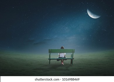 The little girl was walking on a chair in the lawn at night under the moonlight on a beautiful half-moon night.