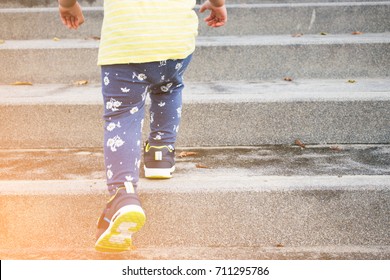 A Little Girl Is Walking Up The Stairs.