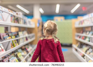 Little Girl Walking Through The Children's Section At The Library Choosing Books