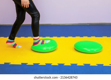 A Little Girl Walks With Her Feet On A Studded Ball In Children's Center As If On A Track