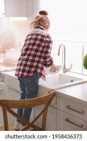 Little Girl Washing Dishes In Kitchen At Home, Back View