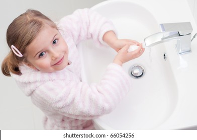 Little girl washing hands in bathroom