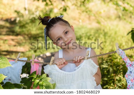 Little girl washing her clothes in the garden