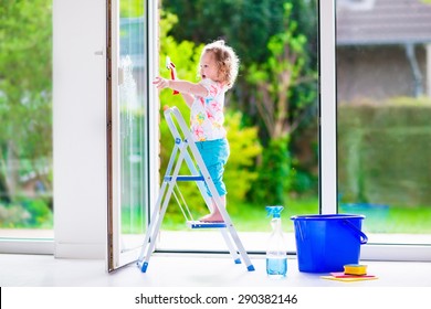 Little Girl Washing A Window. Kids Clean The House. Children Help At Home. Toddler Kid Cleaning Windows And Doors Standing On A Ladder. Child Helping With Housework Holding Sponge And Soap Bottle. 